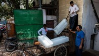 Pekerja meletakkan bongkahan es balok di becak barang. Cukup ringan untuk dikayuh dengan pedal? Tidak ada salahnya untuk mencoba sendiri. Foto dijepret pada 12 Mei 2022. (Xavier Galiana/AFP)