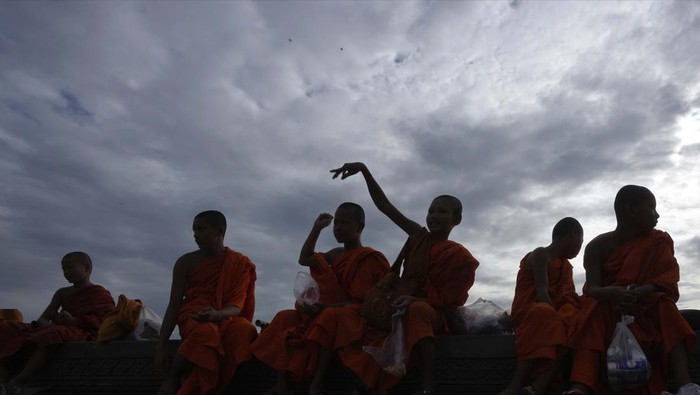 Cambodian Buddhist monks throw corn seeds to feed the birds in front of the Royal Palace, in Phnom Penh, Cambodia, Friday, May 20, 2022. (AP photo/Heng Sinith)