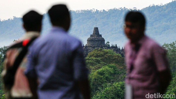 Wisatawan menikmati pemandangan alam dengan latar belakang Candi Borobudur, saat matahari terbit di tempat wisata Bukit Dagi, Borobudur, Jawa Tengah, Jumat (20/5/2022). Terletak di ketinggian 275 meter, Bukit Dagi merupakan tempat terbaik di Borobudur untuk menikmati pemandangan matahari terbit dan keindahan Candi Borobudur.