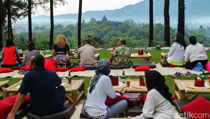 Wisatawan menikmati pemandangan alam dengan latar belakang Candi Borobudur, saat matahari terbit di tempat wisata Bukit Dagi, Borobudur, Jawa Tengah, Jumat (20/5/2022). Terletak di ketinggian 275 meter, Bukit Dagi merupakan tempat terbaik di Borobudur untuk menikmati pemandangan matahari terbit dan keindahan Candi Borobudur.