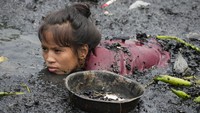 Seorang wanita mencari paku dan potongan logam lainnya dari sisa-sisa rumah yang terbakar di permukiman kumuh yang berada di tepi teluk di distrik Tondo, Manila, Filipina.  