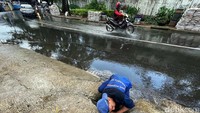 Petugas tampak membersihkan saluran air yang dipenuhi sampah dan lumpur.