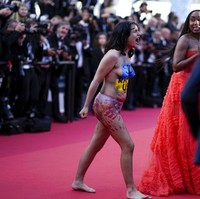 Hanya mengenakan underwear dan melumuri tubuhnya dengan cat merah yang seolah-olah darah, wanita tersebut menuliskan ‘berhenti memperkosa kami’ di tubuh area depannya yang telah dicat dalam warna biru dan kuning seperti bendera Ukraina. Foto: AP/Daniel Cole