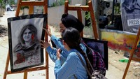 Dua perempuan menghadiri pameran seni yang digelar untuk menghormati mendiang jurnalis Al-Jazeera Palestina, Shireen Abu Aqleh di kota Jenin, Palestina. Ronaldo Schemidt/AFP via Getty Images