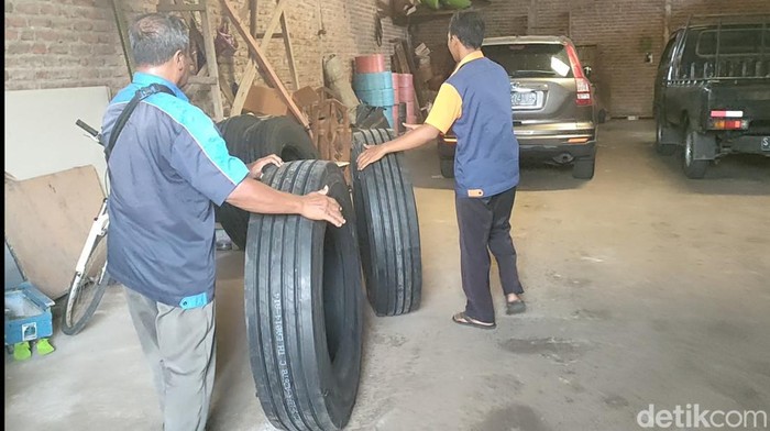 Sejumlah karyawan PO Ardiansyah membawa ban bus di garasi Menganti, Gresik