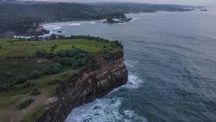Foto aerial kawasan Pantai Karang Bolong, Pacitan, Jawa Timur, Sabtu (21/5/2022). Destinasi wisata Karang Bolong yang menyuguhkan pemandangan tebing dan pantai selatan Jawa Timur tersebut merupakan destinasi favorit di Kabupaten Pacitan. ANTARA FOTO/Hendra Nurdiyansyah/rwa.