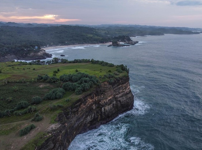 Foto aerial kawasan Pantai Karang Bolong, Pacitan, Jawa Timur, Sabtu (21/5/2022). Destinasi wisata Karang Bolong yang menyuguhkan pemandangan tebing dan pantai selatan Jawa Timur tersebut merupakan destinasi favorit di Kabupaten Pacitan. ANTARA FOTO/Hendra Nurdiyansyah/rwa.