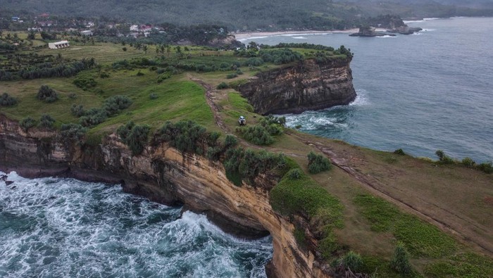 Foto aerial kawasan Pantai Karang Bolong, Pacitan, Jawa Timur, Sabtu (21/5/2022). Destinasi wisata Karang Bolong yang menyuguhkan pemandangan tebing dan pantai selatan Jawa Timur tersebut merupakan destinasi favorit di Kabupaten Pacitan. ANTARA FOTO/Hendra Nurdiyansyah/rwa.