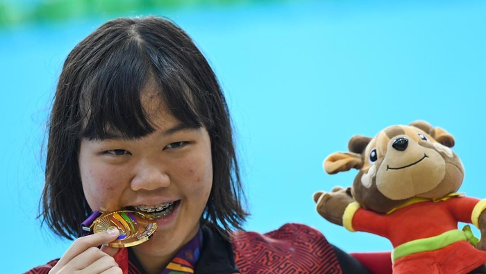 Perenang Indonesia Flairene Candrea Wonomiharjo menggigit medalinya usai upacara pengalungan medali nomor renang 100 meter gaya punggung putri SEA Games 2021 Vietnam di Aquatic Sport Palace, Hanoi, Vietnam, Selasa (17/5/2022). Flairene meraih medali emas setelah finis pertama dengan catatan waktu 1 menit 3,36 detik. ANTARA FOTO/Aditya Pradana Putra/rwa.
