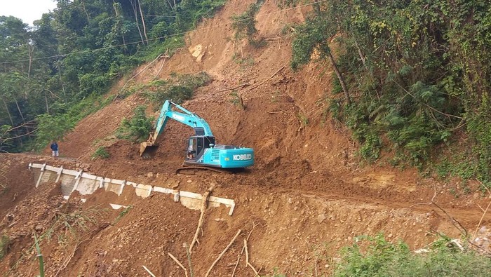 Alat berat membersihkan material longsor di jalan kabupaten, Dusun Plampang II, Kalurahan Kalirejo, Kokap, Kulon Progo, Senin (23/5/2022).