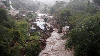 Penampakan sebuah sungai meluap setelah hujan lebat, di samping rumah-rumah yang rusak akibat banjir sebelumnya, di kwaNdengezi dekat Durban, Afrika Selatan.