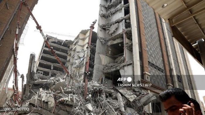Iranians gather at the site where a ten-storey building collapsed in the southwestern city of Abadan on May 23, 2022. - At least four people died and about 80 were trapped under rubble when an unfinished building collapsed in southwestern Iran, officials said. (Photo by TASNIM NEWS / AFP)