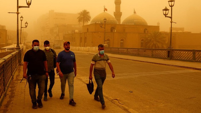 IRAQ-SANDSTORM/ A child sweeps the floor during a sandstorm at the Imam Ali Shrine in Najaf, Iraq, May 23, 2022. REUTERS/Alaa Al-Marjani