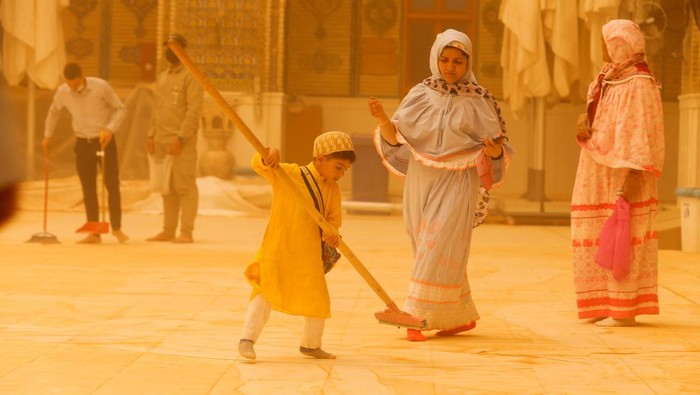 IRAQ-SANDSTORM/ A child sweeps the floor during a sandstorm at the Imam Ali Shrine in Najaf, Iraq, May 23, 2022. REUTERS/Alaa Al-Marjani