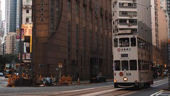 Kereta tram yang warnanya persis dengan gedung di belakangnya.