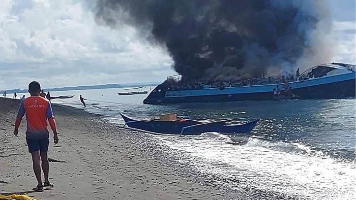 Kapal Pesiar Terbakar di Filipina, 7 Orang Tewas In this handout provided by the Philippine Coast Guard, Coast Guard members check the still smoldering M/V Mercraft 2 after it was towed to an island off the town of Real, Quezon province, Philippines, Monday, May 23, 2022. The passenger ship caught fire as it neared it's port destination in Real, killing several people on board. (Philippine Coast Guard via AP Photo)