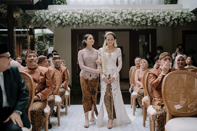 Tak kalah cantik, adik Maudy Ayunda, Amanda Khairunnisa, mengenakan kebaya warna mauve dipadu kain batik saat menggandeng sang kakak menuju tempat akad nikah. Foto: Instagram @maudyayunda