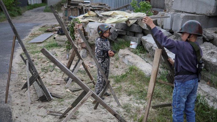Ukrainian children Andrii, 12 and Valentyn, 6, stand in a foxhole as they play Ukrainian military near their houses, amid Russia's invasion, in the village of Stoianka, in Kyiv region, Ukraine May 22, 2022. REUTERS/Gleb Garanich     TPX IMAGES OF THE DAY