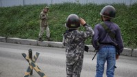 Anak-anak Ukraina, Andrii (12) dan Valentyn (6) memberi hormat saat mereka bermain militer Ukraina di dekat rumah mereka, ditengah invasi Rusia, di desa Stoianka, Kyiv, Ukraina, (22/5/2022).
