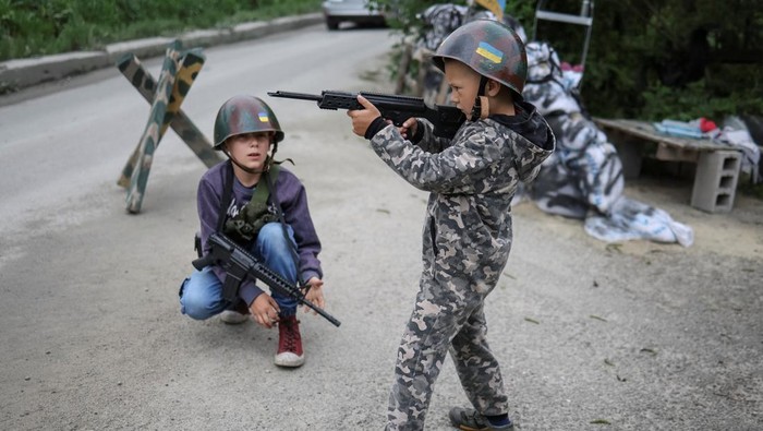 Ukrainian children Andrii, 12 and Valentyn, 6, stand in a foxhole as they play Ukrainian military near their houses, amid Russia's invasion, in the village of Stoianka, in Kyiv region, Ukraine May 22, 2022. REUTERS/Gleb Garanich     TPX IMAGES OF THE DAY
