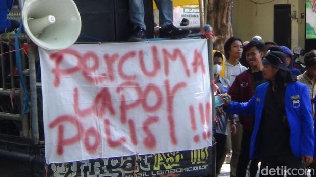 Ratusan aktivis PMII berunjuk rasa di depan Polres Sumenep. Mereka bentangkan spanduk Percuma Lapor Polisi.
