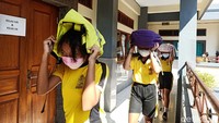 Para siswa keluar ruang kelas sambil melindungi kepalanya menggunakan tas. Mereka keluar ruang kelas saat alarm berbunyi kencang di sekolah tersebut.