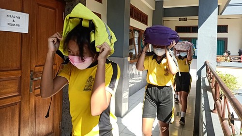 Siswa SD Saraswati 6 Denpasar tampak menutupi kepala mereka dengan tas gendongnya pada Senin (23/5/2022). Hal tersebut merupakan bagian dalam simulasi kebencanaan yang digelar BPBD Kota Denpasar dan SD Saraswati 6 Denpasar