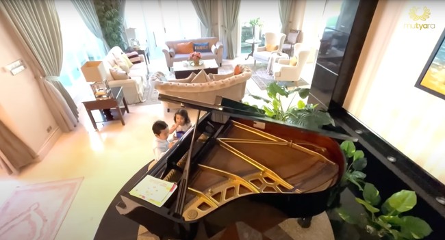 Di dekat ruang tamu tersebut terdapat sebuah piano hitam besar yang membuat ruangan jadi terlihat lebih mewah dan elegan. Piano tersebut biasanya dipakai sang anak untuk bermain sekaligus belajar. Foto: YouTube/THE TYAS FAMILY