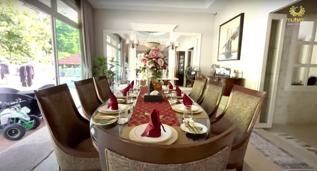 Untuk ruang makan pun Tya dan sang suami memilih meja dan bangku berwarna coklat. Meja makan pun tampak sudah dipenuhi dengan piring, peralatan makan, dan serbet yang sudah tertata rapih. Untuk mempercantik, hiasan berupa vas yang berisi bunga pun ditambahkan di bagian tengah meja makan. Foto: YouTube/THE TYAS FAMILY