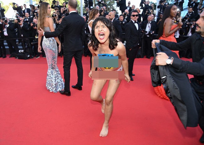 Seorang wanita bikin ulah di karpet merah festival film Cannes. Dia tiba-tiba masuk ke karpet merah dan tidak mengenakan busana. Aksinya tersebut jadi heboh dan pusat perhatian. Foto: Getty Images