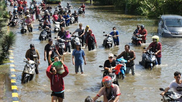 Warga melewati banjir akibay gelombang pasang menerjang pesisir utara yang melumpuhkan aktivitas pelabuhan di pelabuhan Tanjung Mas di Semarang, Jawa Tengah, Selasa (24/5/2022). (Photo by DAFFA RAMYA KANZUDDIN/AFP via Getty Images)