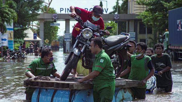 Banjir di area terminal pelabuhan peti kemas Tanjung Emas, Semarang Pekerja menggunakan rakit darurat mengevakuasi sepeda motor di area terminal pelabuhan peti kemas Tanjung Emas yang terendam banjir, menyusul air pasang dan tanggul laut yang rusak, di Semarang, Jawa Tengah, Selasa (24/5/2022). (REUTERS/Budi Purwanto)