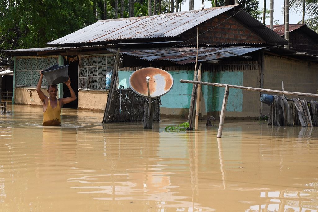 Seorang pria membawa barang-barangnya melewati banjir setelah hujan lebat di distrik Morigaon di negara bagian Assam, India, Minggu (22/5/2022). Banjir adalah ancaman biasa bagi jutaan orang di dataran rendah Bangladesh dan tetangga timur laut India, tetapi banyak ahli mengatakan bahwa perubahan iklim meningkatkan frekuensi, keganasan dan ketidakpastian. (Photo by BIJU BORO/AFP via Getty Images)