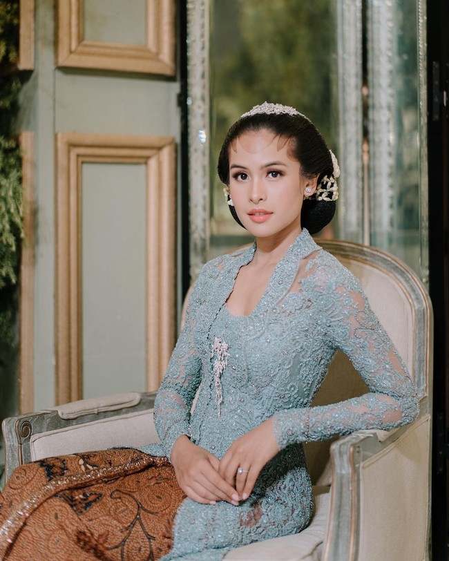Kali ini ia terlihat memakai kebaya biru, batik, hair piece juga paes yang dirias tipis. Foto: Instagram @maudyayunda