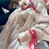 Dress berwarna putih itu tampak cukup panjang dan memiliki motif berbentuk bunga. Pada bagian pergelangan tangan, dada, dan bawah dress terlihat dipermanis dengan sentuhan pita berwarna merah muda. Foto: Instagram/@nadinelist