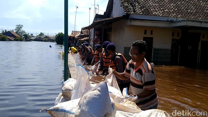 Warga bersama petugas bergotong royong menambal tanggul jebol di sungai Meduri, Kota Pekalongan, yang membuat banjir rob, Selasa (24/5/2022).