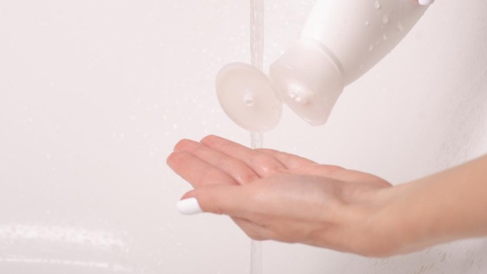 White bottle gel shower in hands water bath cosmetic care body
