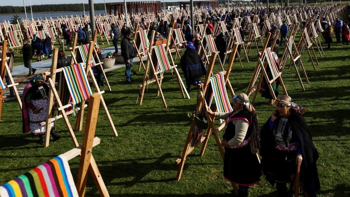 Wanita Chile Pecahkan Rekor Bikin Kain Tenun Terpanjang Dunia Indigenous Mapuche women work in their looms while seeking to break a world record by gathering loom weavings that together will measure more than 1 kilometre in length in Puerto Saavedra, Chile, May 21, 2022. REUTERS/Juan Gonzalez