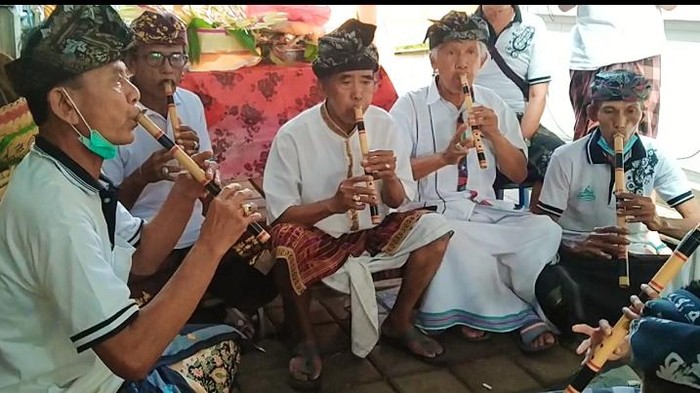 Atas permintaan detikBali, dua orang pemain gong suling yang masih tersisa memainkan gong suling saat odalan di Pura Pasar Jembrana, Bali, Selasa (24/5).