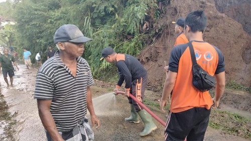 Petugas BPBD Tabanan dan warga Banjar Dadia, Desa Babahan, Tabanan, Bali, membersihkan material longsor yang menutup ruas jalan pada Rabu (25/5).