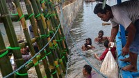 Sejumlah orang sibuk menata karung pasir di lokasi tanggul yang jebol.