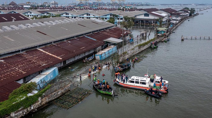 Tanggul Jebol di Tanjung Emas Semarang Ditambal Personel kepolisian dari Polsek Kesatuan Pelaksanaan Pengamanan Pelabuhan (KP3) Tanjung Emas Semarang bersama warga dan relawan bergotong royong menutup tembok kawasan industri atau tanggul yang jebol dengan konstruksi pagar bambu dan karung berisi pasir dan batu di kawasan industri Pelabuhan Tanjung Emas Semarang, Jawa Tengah, Rabu (25/5/2022). PT Pelindo (Persero) Regional 3 Tanjung Emas Semarang menyiapkan 3.600 karung berisi pasir dan batu serta pagar bambu untuk membuat tanggul darurat guna menutup tanggul yang jebol. ANTARA FOTO/Aji Styawan/tom.