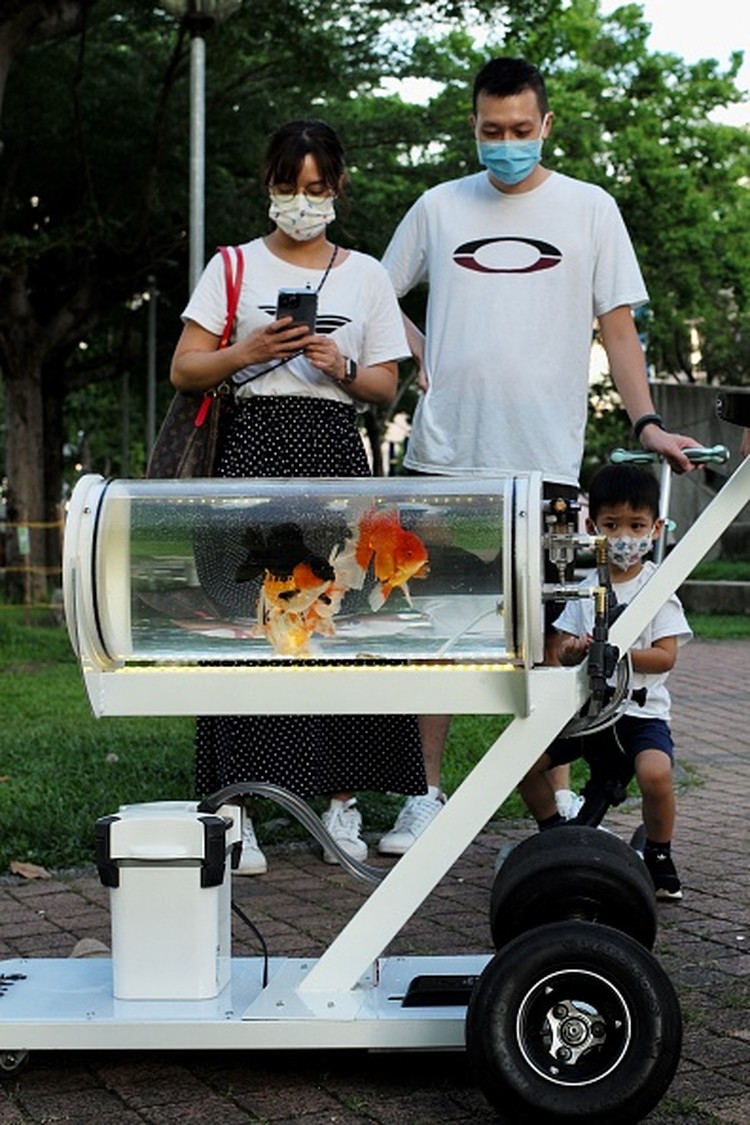 This picture taken on May 19, 2022 showing Jerry Huang walking with his fish tank trolley at a park in Taichung, central Taiwan. (Photo by Sam Yeh / AFP) (Photo by SAM YEH/AFP via Getty Images)