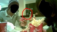 Di tengah hiruk pikuk pengunjung di restoran KFC, dua pria ini berhasil menangkap sesosok wajah yang mengamati mereka dari jendela kaca, ketika mereka tengah mengabadikan foto bersama makanan. Hii.. seram! Foto: Pool/Site News