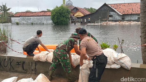 Hujan tidak menyurutkan TNI-Polri, Satpol PP dan warga menyelesaikan tanggul darurat di Kota Pekalongan untuk mengantisipasi banjir rob susulan, Kamis (26/5/2022).