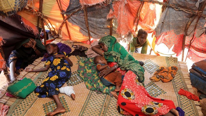 Amina Hassan Aden sits with her children Yonis Saleban, 1, Abdulahi Saleban, 3, and Isnino Saleban, 9, inside their makeshift shelter at the Kaxareey camp for the internally displaced people in Dollow, Gedo region of Somalia May 24, 2022. Picture taken May 24, 2022. REUTERS/Feisal Omar