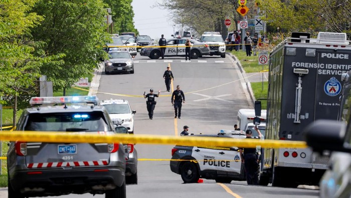 Police officers work at the scene where police shot and injured a suspect who was walking down a city street carrying a gun, as four nearby schools were placed on lockdown, in Toronto, Ontario, Canada, May 26, 2022. REUTERS/Chris Helgren