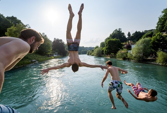 TOPSHOT - Young men jump into the river Aare on June 21, 2017 in Bern.

Europe sizzled in a continent-wide heatwave with London bracing for Britains hottest June day since 1976 as Portugal battled to stamp out deadly forest fires. Cooler weather was aiding their efforts, but thermometers were still hovering around 35 degrees Celsius (95 degrees Fahrenheit) -- a level matched across oven-like swathes of Europe, including Italy, Austria, the Netherlands and even alpine Switzerland. / AFP PHOTO / Fabrice COFFRINI (Photo credit should read FABRICE COFFRINI/AFP)