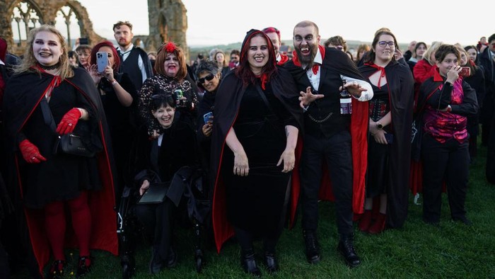 WHITBY, ENGLAND - MAY 26: People dressed as vampires react after a successful attempt to break the world record with 1369 counted at Whitby Abbey  on May 26, 2022 in Whitby, England. To coincide with the anniversary of the first publication of Bram Stoker’s Dracula 125 years ago (26 May 1897), English Heritage attempt to set a new world record for the most amount of vampires gathered in one place. The current record stands at 1039 vampires set at Doswell in Virginia, USA in 2011. Strict rules on attire govern the record attempt and traditional vampire dress is defined as: black trousers, black skirt or a dress, black shoes, waistcoat, shirt, black cape or collared overcoat, and fangs on the top set of teeth. (Photo by Ian Forsyth/Getty Images)Ribuan 'Vampir' Berkumpul di Inggris untuk Pecahkan Rekor Dunia