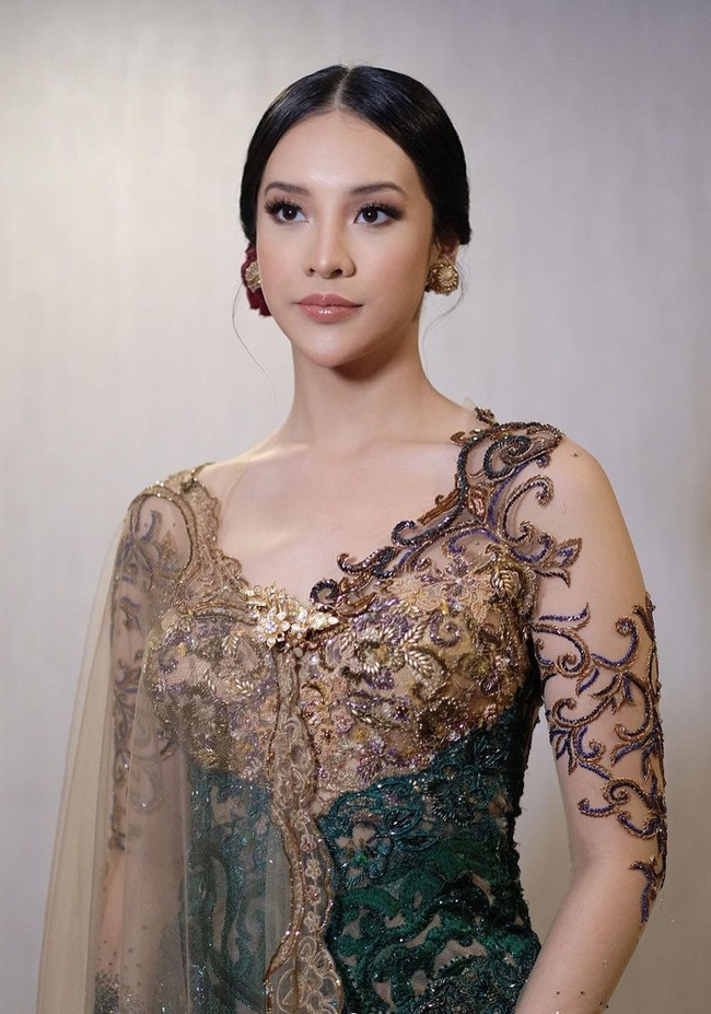 Kebaya lengan panjang berwarna hijau dan gold itu memiliki potongan kerah berbentuk v. Salah satu lengannya terdapat tambahan kain tile menjuntai dari bagian bahunya yang mempermanis tampilan kebaya. Foto: Instagram